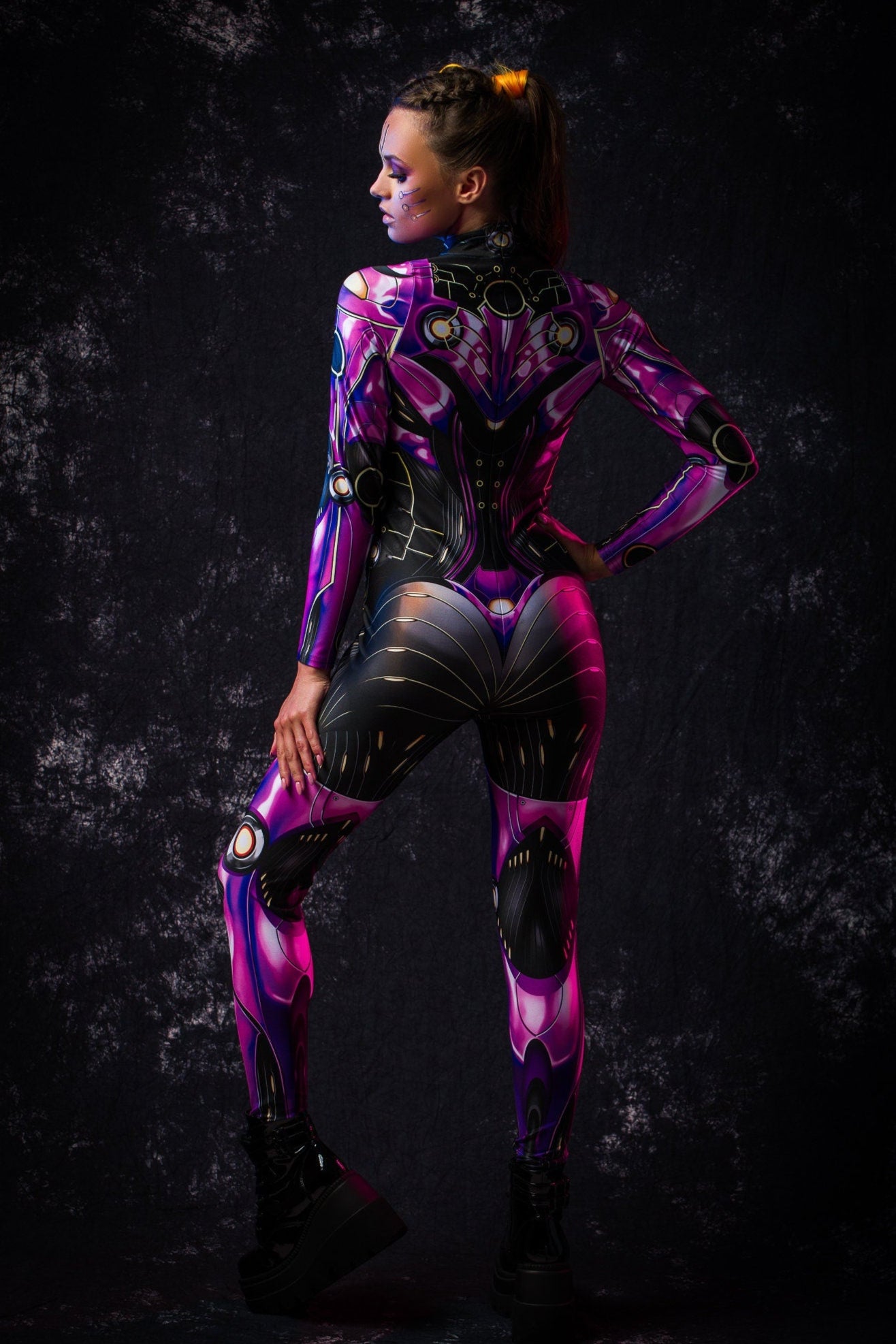 Energetic rear pose of a woman in a violet android catsuit, highlighting the suit’s futuristic design and perfect fit for cosplay and themed events.