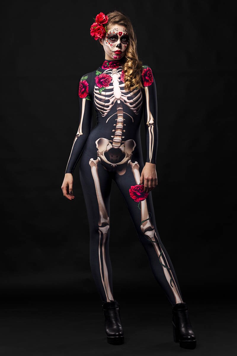 Woman wearing a skeleton-print bodysuit with floral rose accents and cloak, Day of the Dead-inspired, with sugar skull face paint and a rose crown.