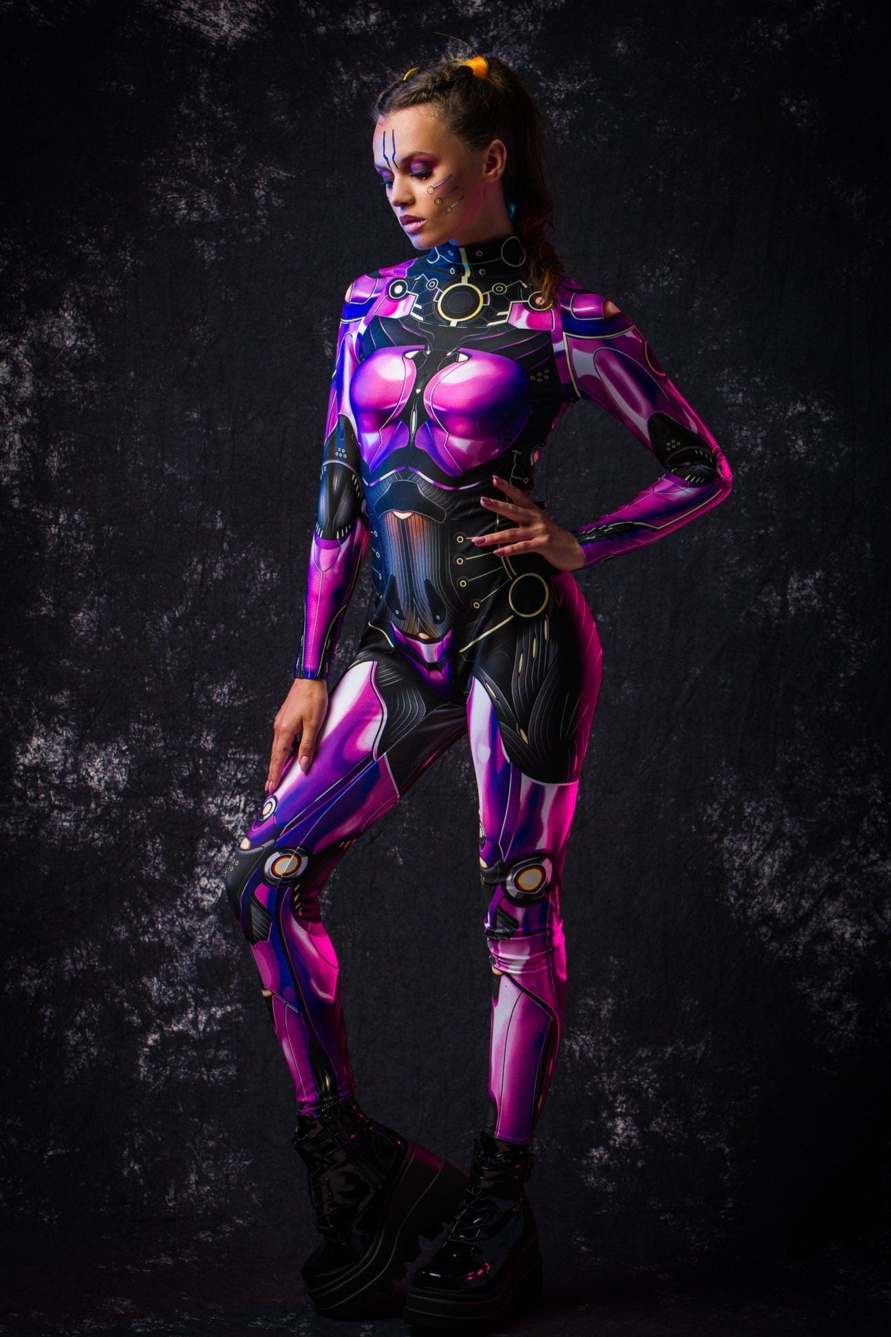 Profile view of a woman in a violet android catsuit, showing the sleek silhouette and intricate design details of the futuristic full body costume.