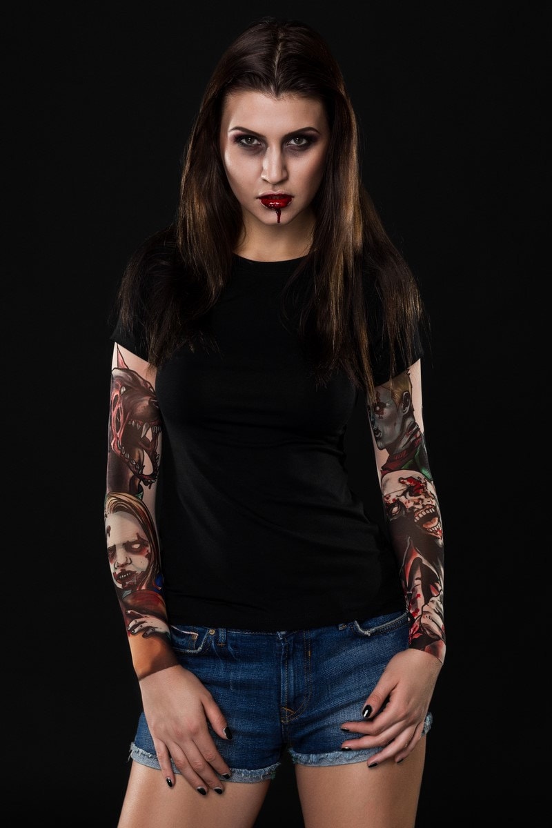 Zombie Halloween T-shirt for women with tattoo mesh sleeves, featuring horror-inspired zombie designs, perfect for Halloween or costume parties.