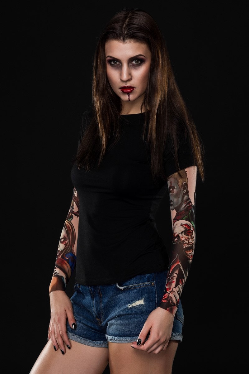 Woman posing in the Zombie Halloween T-shirt with tattoo mesh sleeves, showcasing the detailed zombie designs on the sleeves, great for Halloween or as a fun, casual top.