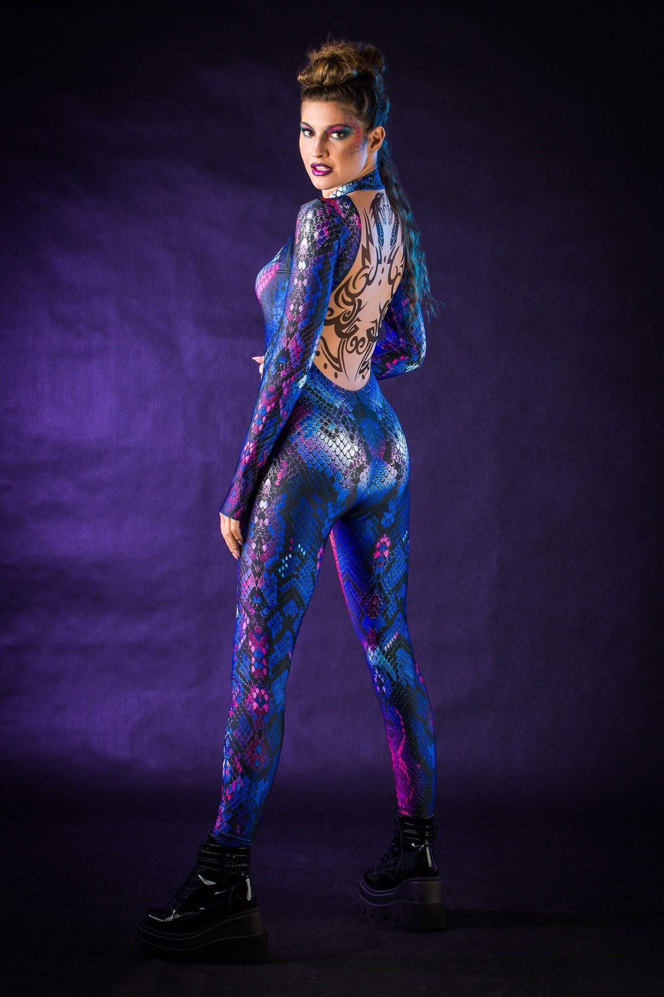 Woman wearing the Blue Snake costume, a full-body snake skin jumpsuit with tattoo details on the back, perfect for Halloween or standout festival outfits.