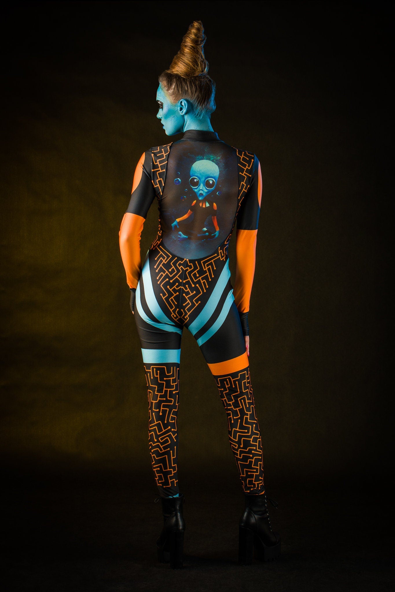 Woman wearing the Blue Alien Halloween costume, a full-body UFO-themed jumpsuit with tattoo details on the back, perfect for Halloween parties or alien-themed cosplay.