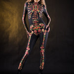 Woman posing in the Flower Skeleton costume, showcasing the colorful skeleton design with orange, yellow, and green floral patterns, great for Halloween or as a standout festival outfit.