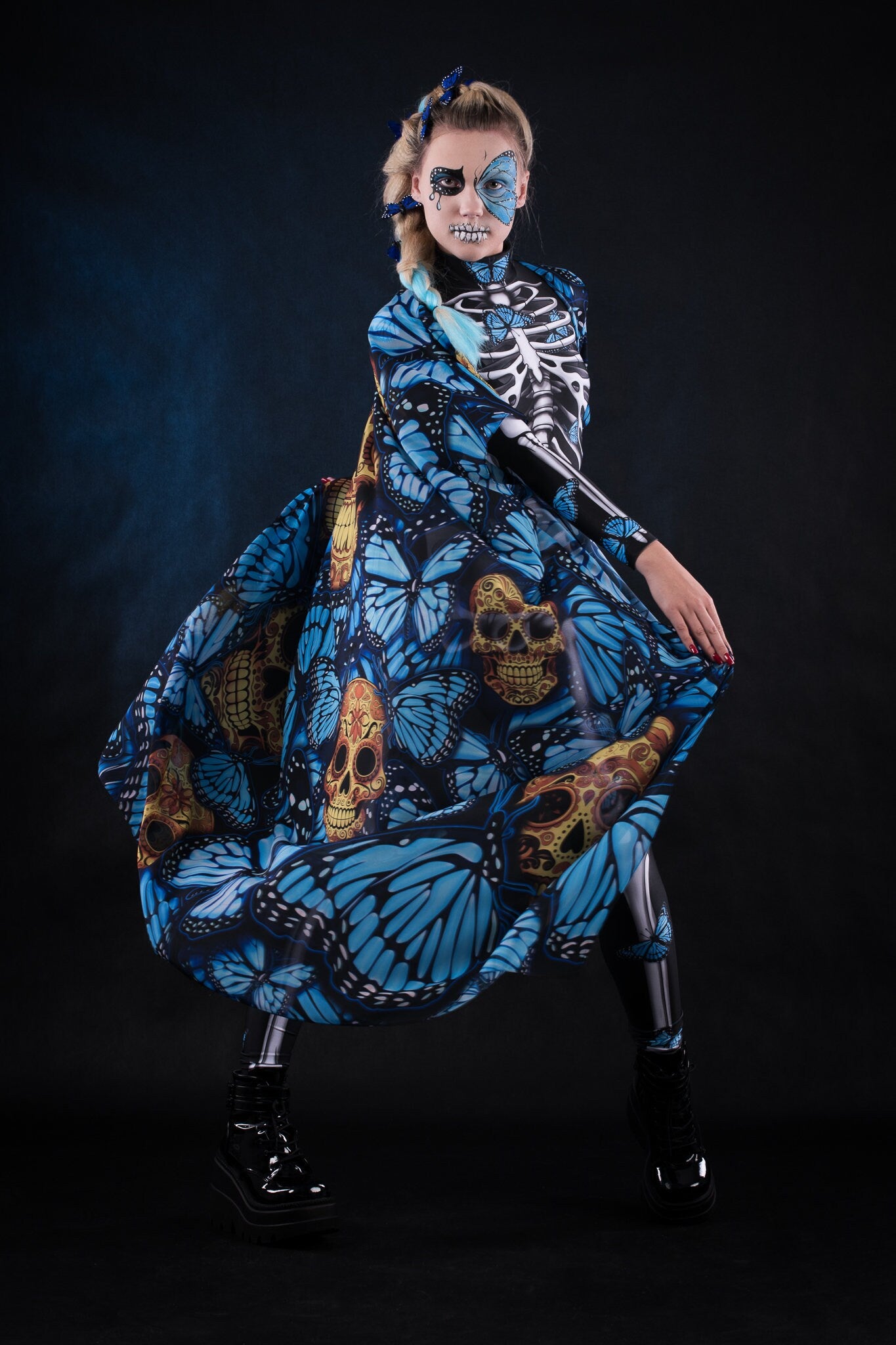 Woman posing in the Blue Monarchy Butterflies Halloween cape, highlighting the dramatic flow and vibrant butterfly details, great for a Day of the Dead-inspired look or festival wear. Woman dancing.